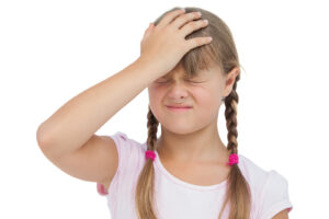 Little girl suffering from headache and touching her head on white background